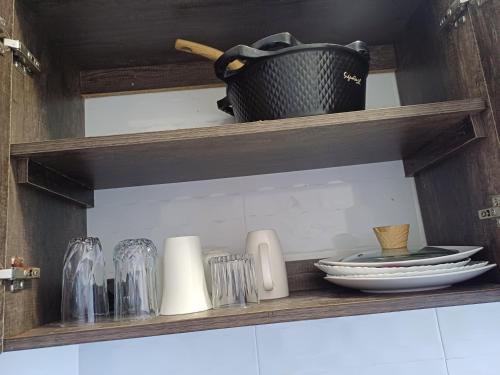 a shelf with plates and glasses and a basket on it at Glamorous Homes in Bamburi