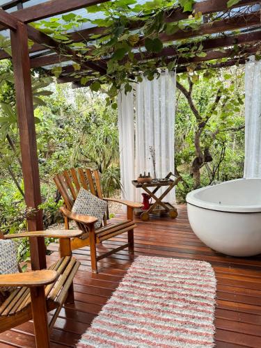 a bathroom with a tub and a chair and a bath tub at Pariká Pousada in Alto Paraíso de Goiás