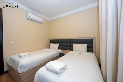 two beds in a room with white sheets at The Expert in Ocean Blue Near Airport in Cairo