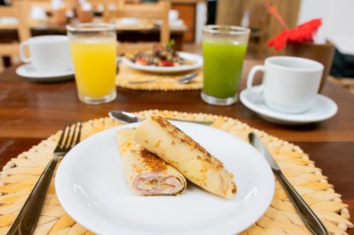 a plate with a sandwich on a table with drinks at CasaLô Hotel in Jericoacoara