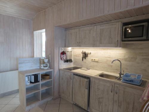 a kitchen with wooden cabinets and a sink at Haus Evelyn in Rheinsberg