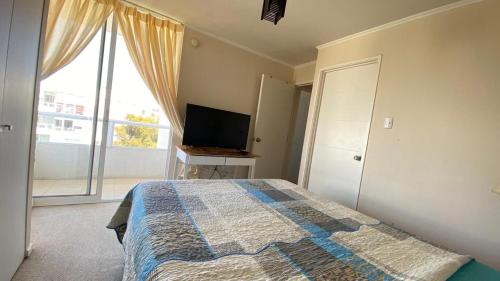a bedroom with a bed and a flat screen tv at departamentos La Serena in La Serena