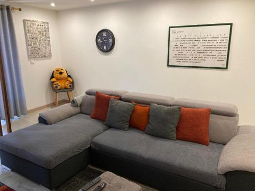 a couch in a living room with a clock on the wall at Casinha da Avenida in Minde