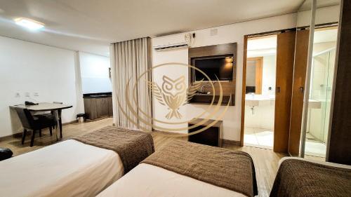 a hotel room with two beds and a table at Coruja Imob - Flat Crystal Place in Goiânia