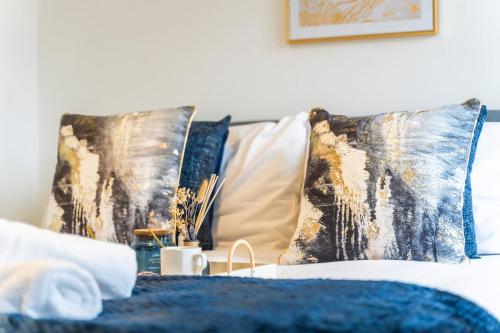 a bed with blue and gold pillows on it at The Cerulean Manor, City Centre House, Large Drive, Free Parking, WiFi, Netflix in Coventry