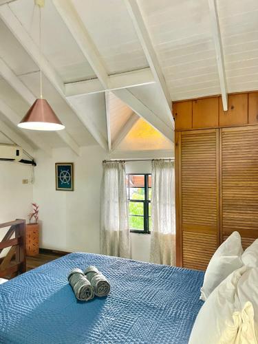 a bedroom with a blue bed with two towels on it at Bananaquit Tobago -Stay Near the Beach in Crown Point