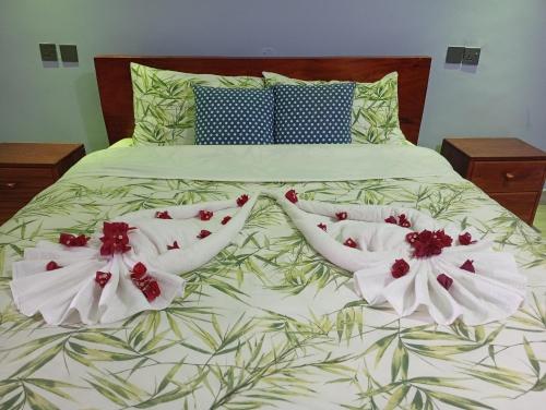 a bed with white sheets and red flowers on it at Lala Inn Kikopey in Gilgil