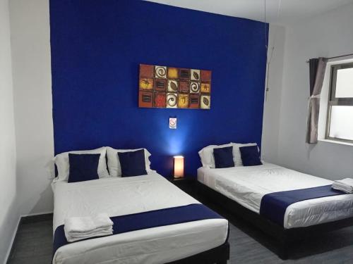 two beds in a room with a blue wall at Hotel Gandag in Orizaba