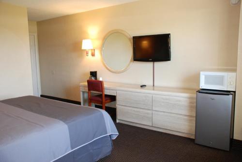 a hotel room with a bed and a desk with a tv at Apple Tree Inn in Lindale