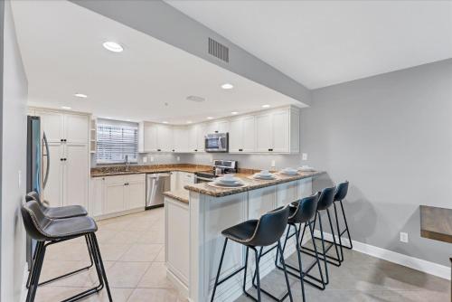 a kitchen with white cabinets and bar stools at 50 Meredith #7 in Manasota Key