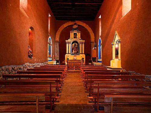 an empty church with wooden pews and a altar at San Agustin Monasterio de la Recoleta in Urubamba