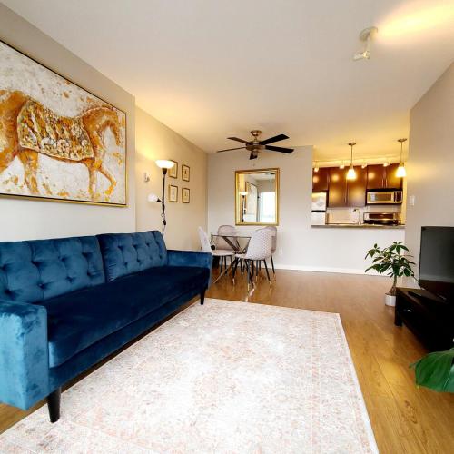 バンクーバーにあるCharming Abode Downtown Vancouverの青いソファのあるリビングルームとダイニングルーム
