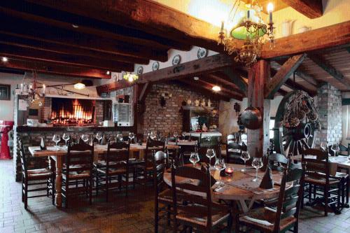 a restaurant with wooden tables and chairs and a chandelier at Hotel Restaurant D'Hofstee in Zuienkerke