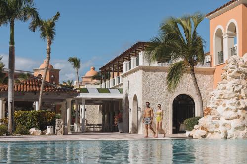 two men standing in a swimming pool in front of a house at Sanctuary Cap Cana, a Luxury Collection Resort, Dominican Republic, Adult All-Inclusive in Punta Cana