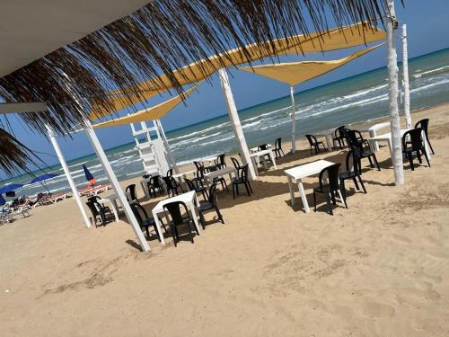 a group of tables and chairs on the beach at Hotel Borina by Isola dei sapori in Foce Varano