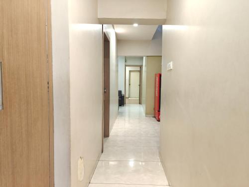 a hallway with white walls and a hallway with a red door at Central Inn, Kolhapur in Kolhapur