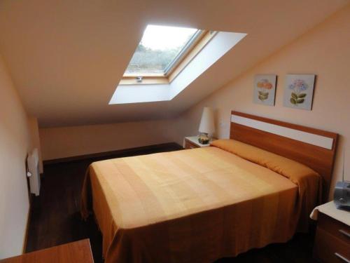 a bedroom with a large bed with a skylight at Apartamento Playa Langosteira in Fisterra