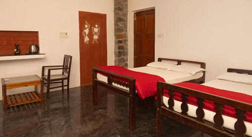 a room with two beds and a table and a chair at Pathayam Inn in Tiruvannāmalai