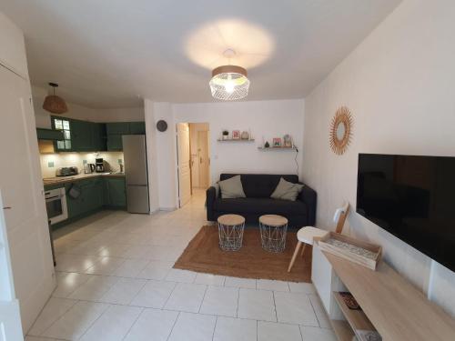 a living room with a couch and a kitchen at T3 Jardin Piscine Plage Clim et Parking in Six-Fours-les-Plages