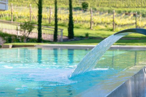 a water fountain in a swimming pool at Hotel Goldene Traube in Termeno