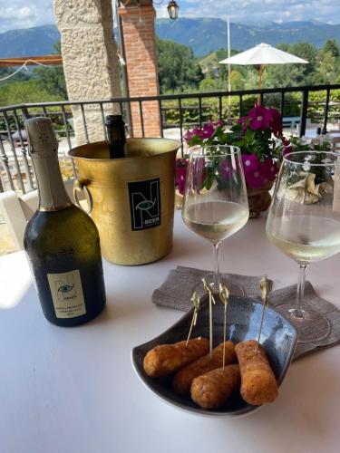 a table with two glasses of wine and a plate of food at Asolo Norah's Hill Agri Rooms in Caenere