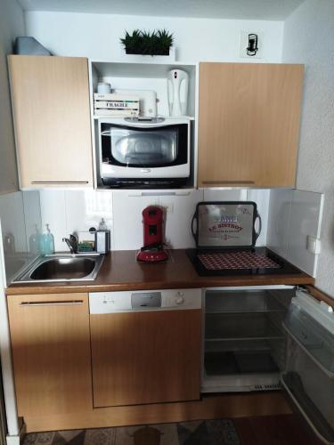 une petite cuisine avec un micro-ondes et un évier dans l'établissement Résidence Le Pic du Midi - maeva Home - Appartement 3 pièces 6 personnes - Confort MAE-1891, à La Mongie