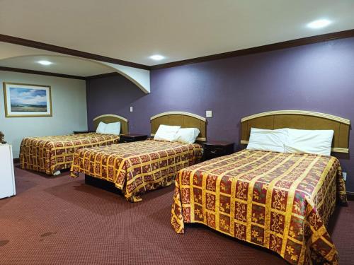 a hotel room with two beds and purple walls at American Inn & Suites By Capital O Victoria US-59 in Victoria