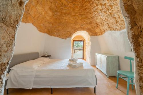 a bedroom with a bed and a window in a cave at Trullo dei Beneficati By Vivimy in Taviano