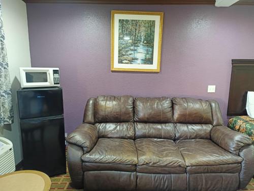 a brown leather couch in a room with a microwave at American Inn & Suites By Capital O Victoria US-59 in Victoria