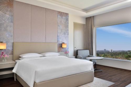 a bedroom with a white bed and a large window at Courtyard by Marriott Bhopal in Bhopal