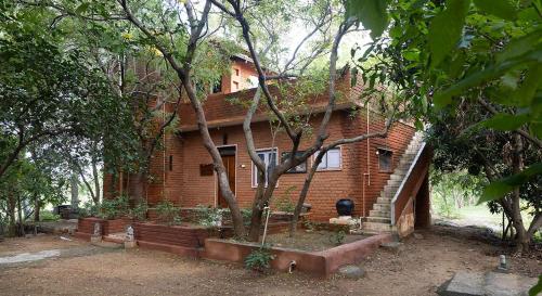 a brick house with a tree in front of it at Pathayam Inn in Tiruvannāmalai