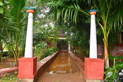a row of columns in a garden with palm trees at Pathayam Inn in Tiruvannāmalai