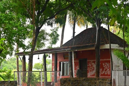 a red and white house with trees behind a fence at Pathayam Inn in Tiruvannāmalai