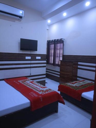 a bedroom with two beds and a flat screen tv at New Gayatri place Near by prem mandir in Dānītola