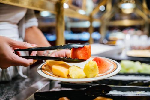 a person holding a plate of fruit on a table at Virgin River Casino and Lodge in Mesquite