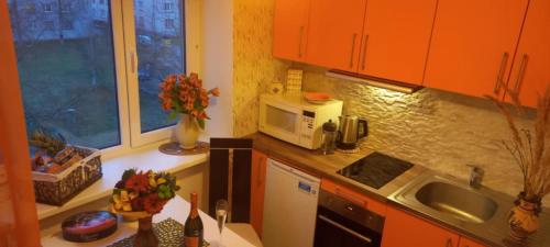 a kitchen with orange cabinets and a microwave at NEW JÕHVI AREA DESIGN STUDIO APARTMENT,RENOVATED 2025, 5min JÕHVI Centre, 10min ALUTAGUSE,Pannjärve,Tartu maraton,30min Kiviõli slalom centre in Ahtme