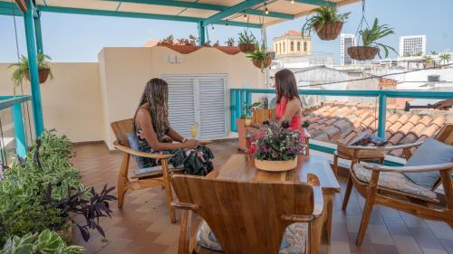 two women sitting at a table on a balcony at Posada La Fe in Cartagena de Indias