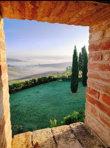 a view of a field through a brick window at PassionToscane in San Giovanni dʼAsso