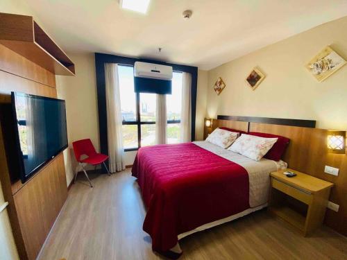 een slaapkamer met een groot bed met een rode deken bij Flat Comfort Hotel Taguatinga 906 in Brasilia