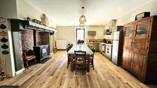 une cuisine avec une table avec des chaises et un réfrigérateur dans l'établissement Gîte de France La maroussie 3 épis - Gîte de France 11 personnes MAE-5091, à Salon-la-Tour