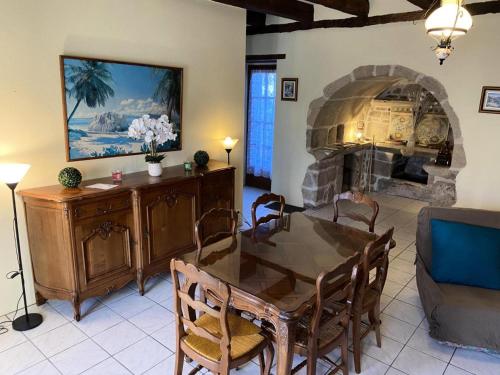 a living room with a table and a stone fireplace at Gîte de France à Darazac 2 épis - Gîte de France 2 personnes MAE-5181 in Darazac