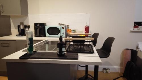 a kitchen with a table with a bottle of beer and a microwave at UNESCO Drogheda 3 Bed in Drogheda