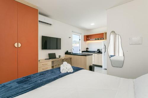 Un dormitorio con una cama grande y una cocina. en Studios Montblanc Campeche, en Florianópolis