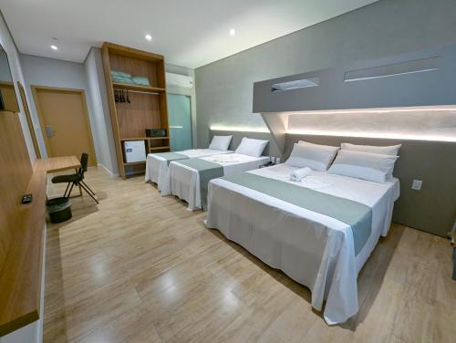 a hotel room with four beds and a desk at Hotel Jardim Iracema in Teófilo Otoni