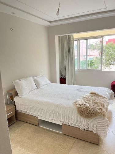 a white bedroom with a large bed and a window at Centre D'estivage Imi Ouaddar in Agadir nʼ Aït Sa
