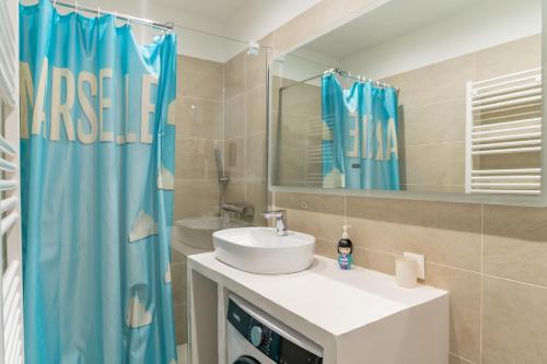 La salle de bains est pourvue d'un lavabo et d'un rideau de douche bleu. dans l'établissement Quartier historique, le Charme du Panier, à Marseille