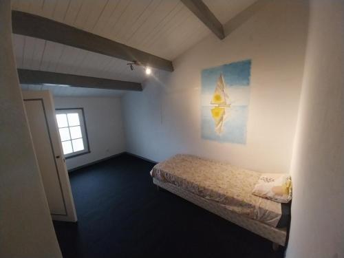 une petite pièce avec un lit et une fenêtre dans l'établissement jolie maison charentaise, à Marennes