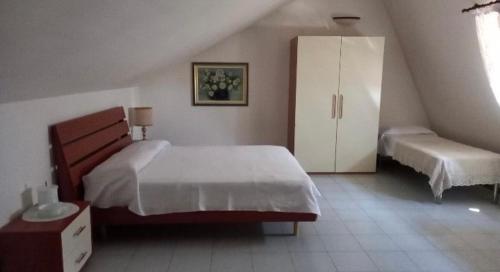 a bedroom with a large white bed and a cabinet at Appartamento Hellas in Marotta