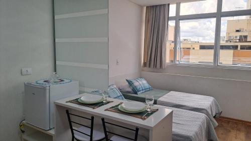 een kleine kamer met een bed en een tafel met stoelen bij Flat Centro de Curitiba Rua 24 horas in Curitiba