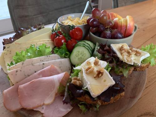 a plate of food with meats and vegetables and grapes at De Logeerkamer Gapinge in Gapinge